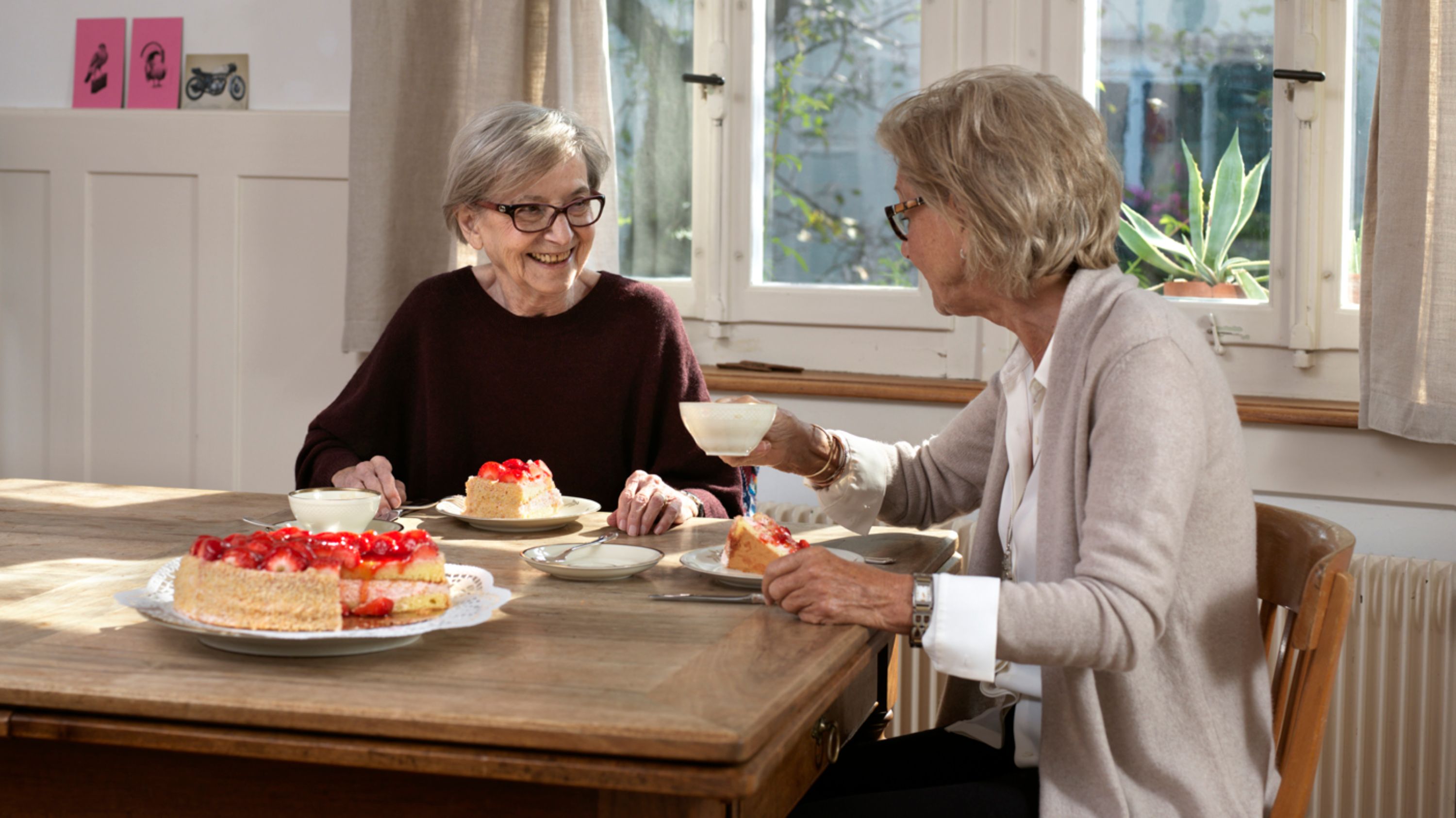 Zwei Frauen sitzen an einem Tisch und essen Torte