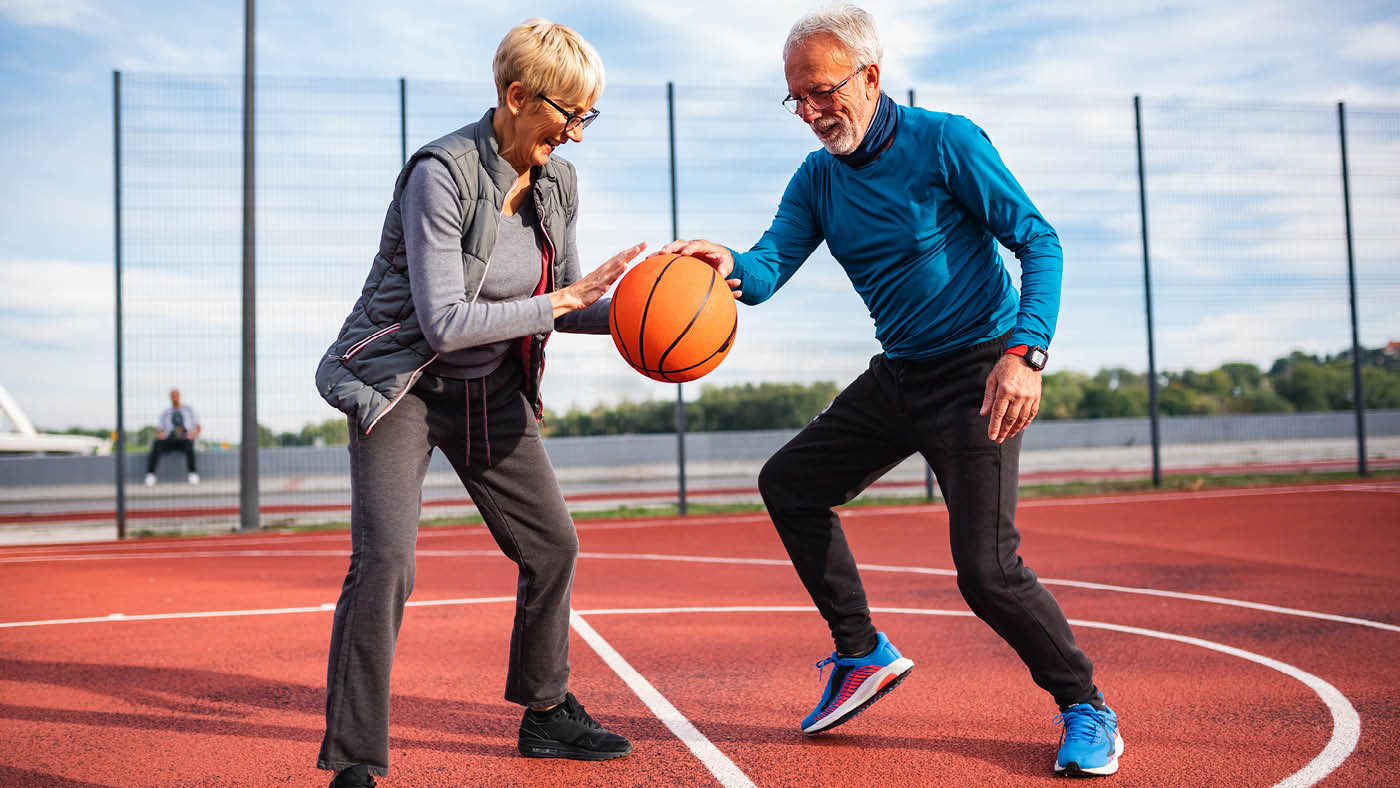 Un couple âgé joue au basket-ball.