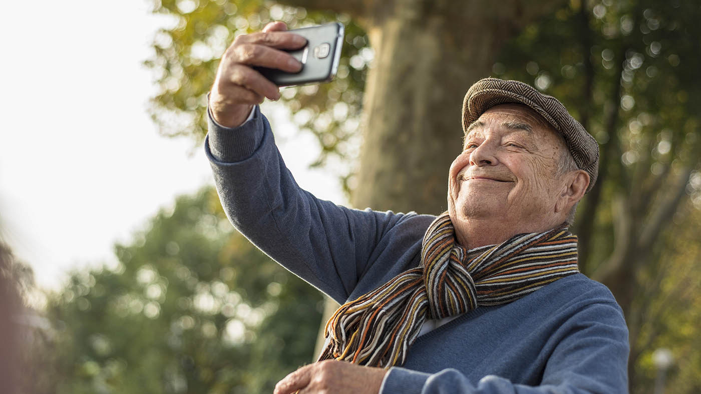 Un anziano si fa un selfie con lo smartphone.
