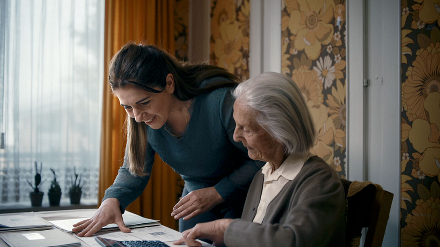 Eine junge Frau hilft einer Seniorin bei ihren Rechnungen.