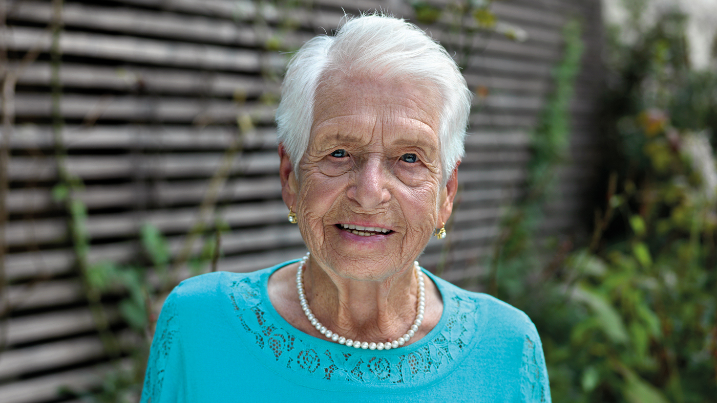 Una signora in età avanzata con camicetta turchese e capelli bianchi
