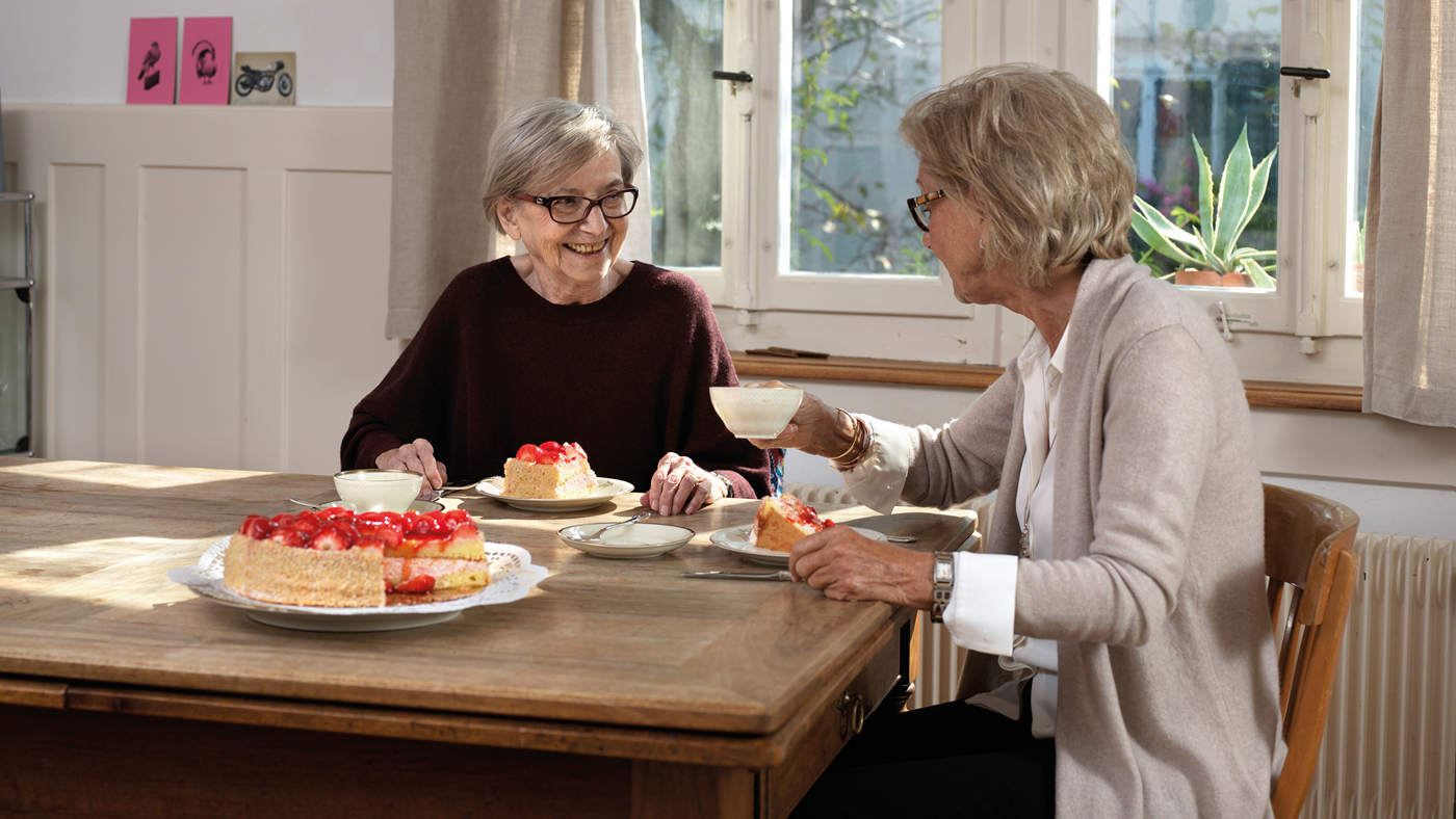 Due donne anziane che mangiano una torta.