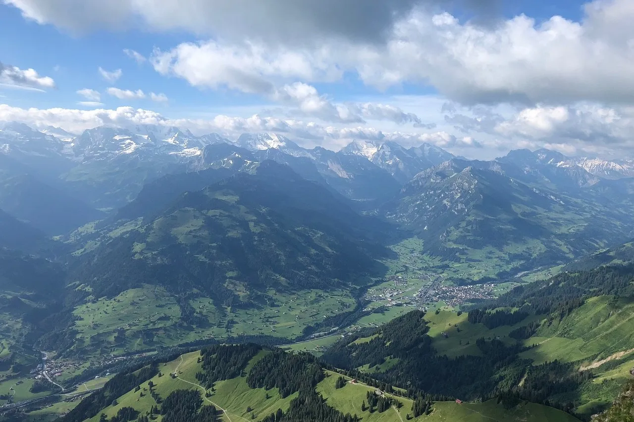 Bild mit Sicht von oben ins Simmental mit seinen Dörfern und Bergen.
