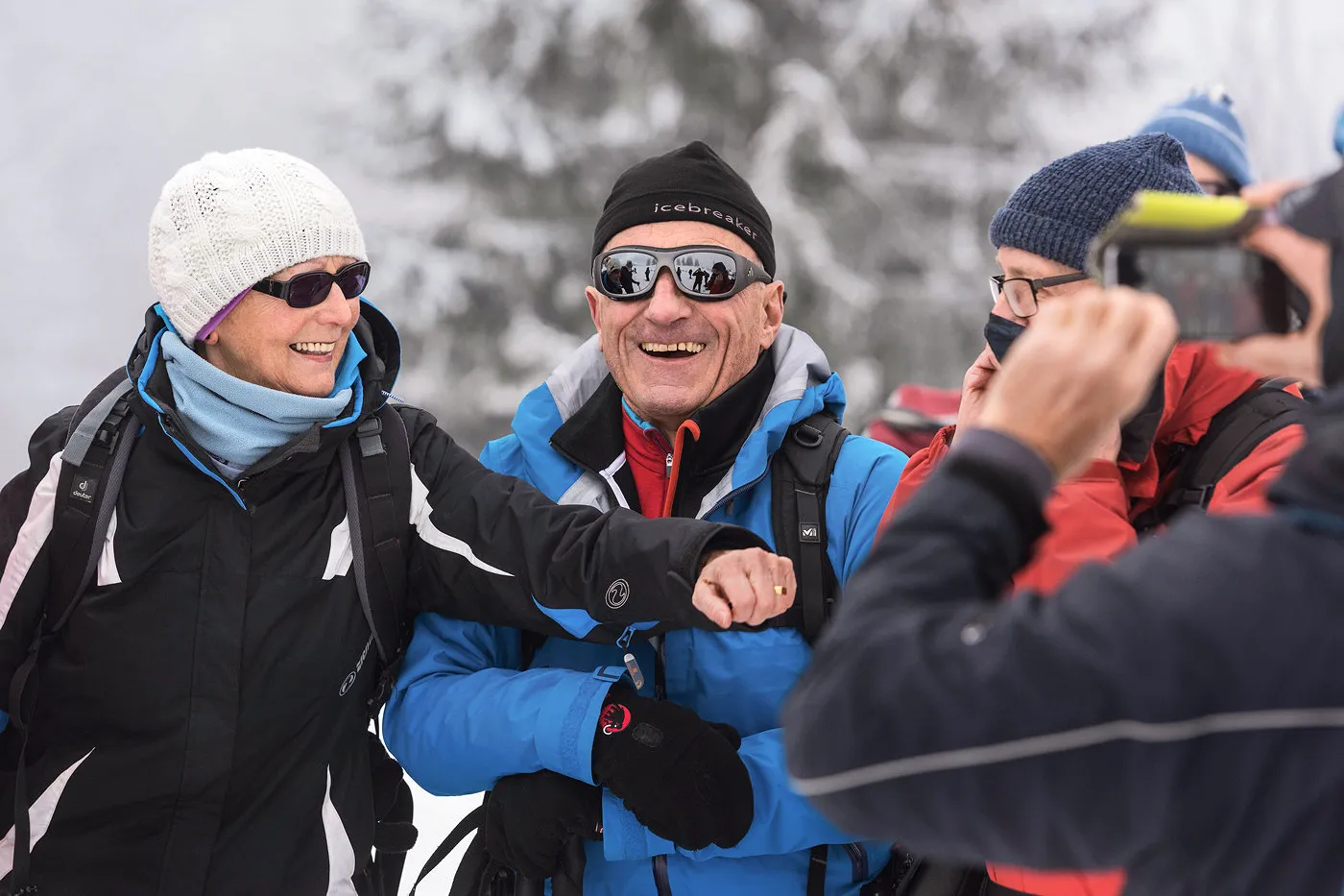 Bild Eine Gruppe winterlich gekleideter älterer Menschen, umgeben von einer schönen Winterlandschaft, diskutiert und lacht miteinander.