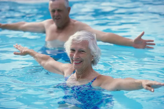 Bild eine Frau und ein Mann stehen bis zum Hals im Wasser und strecken die Arme seitwärts aus.