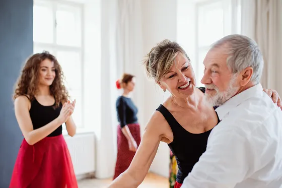 Bild ein Paar tanzt gemeinsam. Sie werden angeleitet von einer Flamencotanzlehrerin, welche den Rhythmus klatscht.