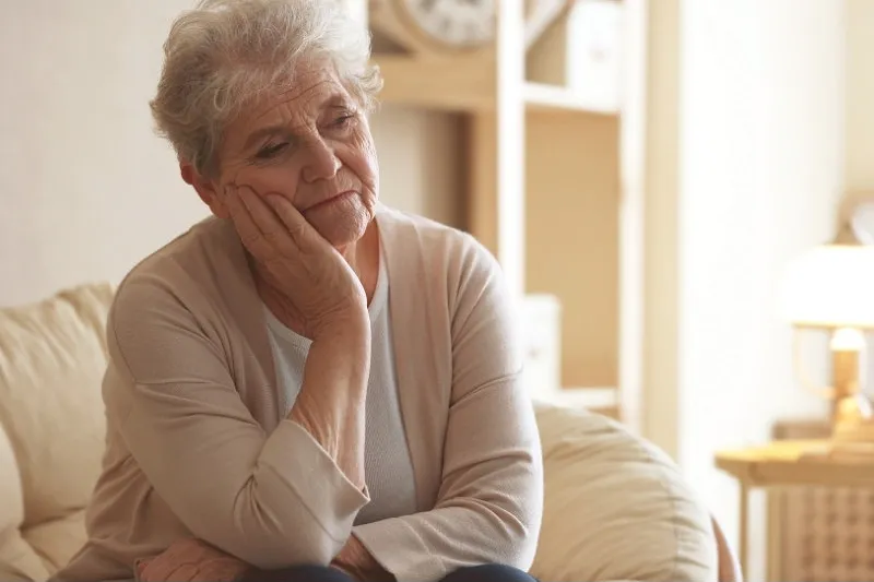 Das Foto zeigt Margrit, wie sie nachdenklich und traurig auf dem Sofa sitzt.
